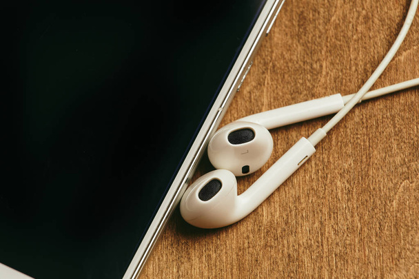 Auriculares en el oído con macro smartphone
 - Foto, Imagen