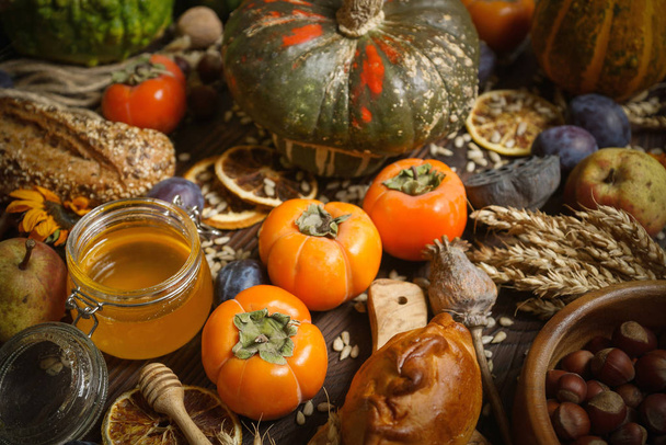 Pumpkins, persimmon, cereals, bread, seeds and nuts on a wooden background, Harvest, Autumn - 写真・画像