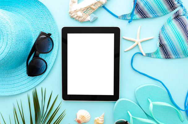 Top view summer ocean vacation concept mockup. Tablet pc on a blue background with womens beach accessories - Photo, Image