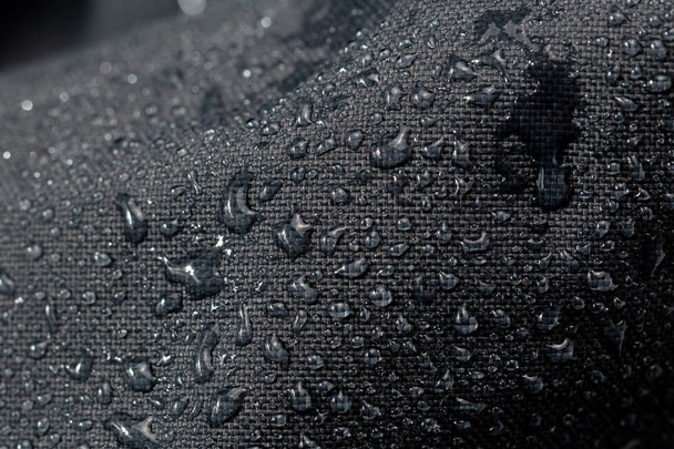 dark gray waterproof hydrophobic cloth closeup with water drops selective focus background - Foto, afbeelding