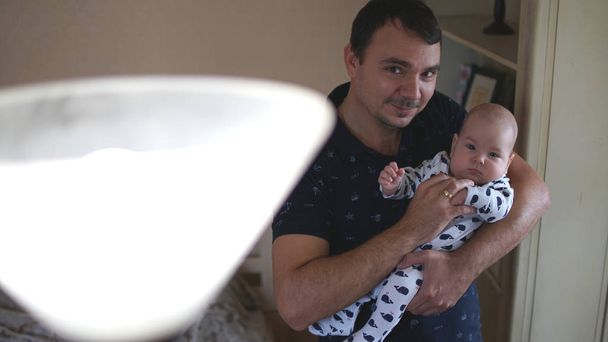 Retrato del joven amante sosteniendo al bebé en casa con lámpara en primer plano
. - Foto, imagen