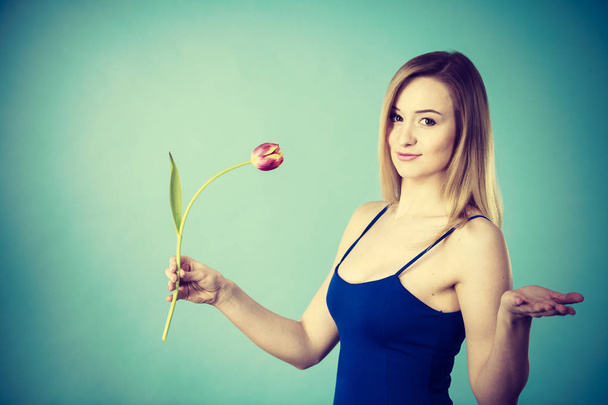 Shot on blue of woman holding tulip - Фото, зображення