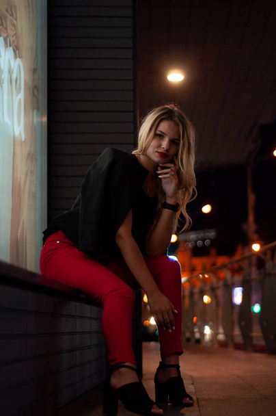 Sexy young beauty woman posing over night city illuminated street background. Vacation holidays. Young stylish woman blonde with long hair - Fotó, kép