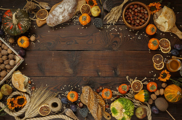 Kürbisse, Kaki, Getreide, Brot, Samen und Nüsse auf hölzernem Hintergrund, Ernte, Herbst - Foto, Bild