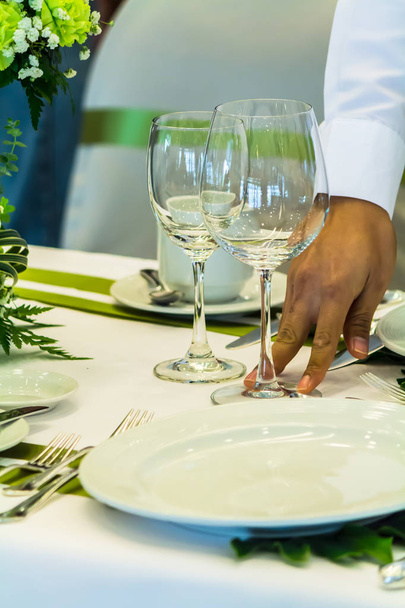Официант украшает и накрывает праздничный стол в ресторане
 - Фото, изображение