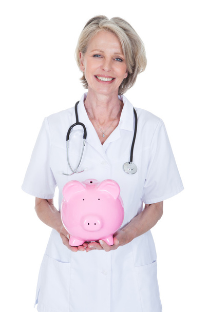 Mature Female Doctor Holding Piggybank - Photo, Image