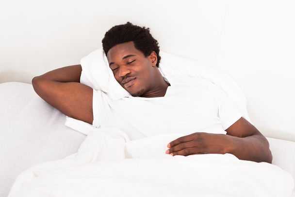 Young African Man Sleeping In Bed - Фото, изображение