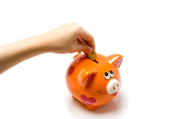The child puts a coin in the piggy Bank on a white background - Photo, Image