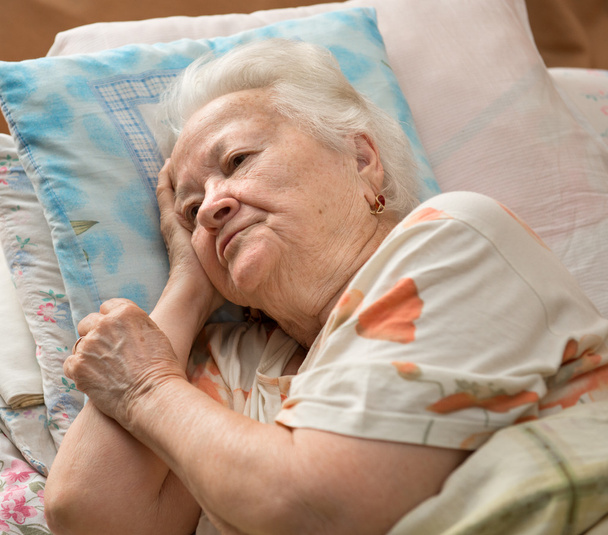 Vanhempi nainen makaa sängyssä
 - Valokuva, kuva