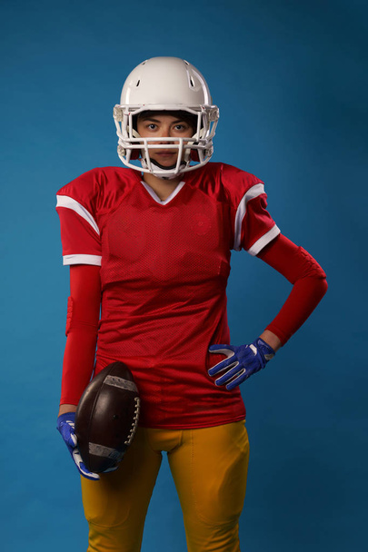 Photo of young american woman football player in white helmet, sportswear with ball in her hand - Foto, imagen