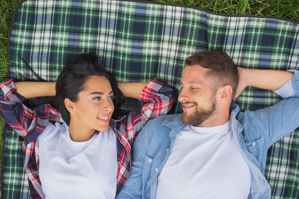 loving couple lie on a plaid in the park and hugging, handsome guy and girl - Photo, Image