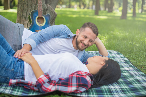 loving couple lie on a plaid in the park and hugging, handsome guy and girl - Foto, immagini