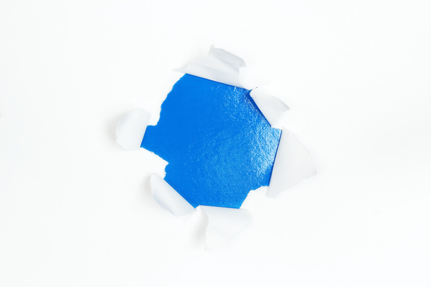 Blue hole in white paper with ragged edges - Photo, Image