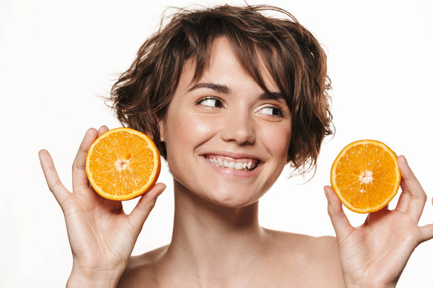 Beautiful young pretty woman with healthy glowy skin posing isolated over white wall background holding orange. - Valokuva, kuva