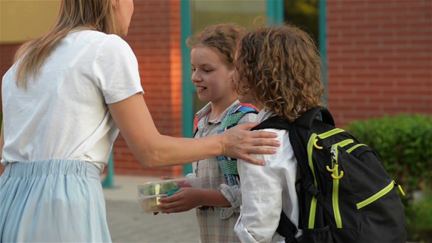 Edukacja, Rodzina i opieka koncepcja. Kochająca matka dając jej Kids School lunch w pobliżu szkoły. - Materiał filmowy, wideo