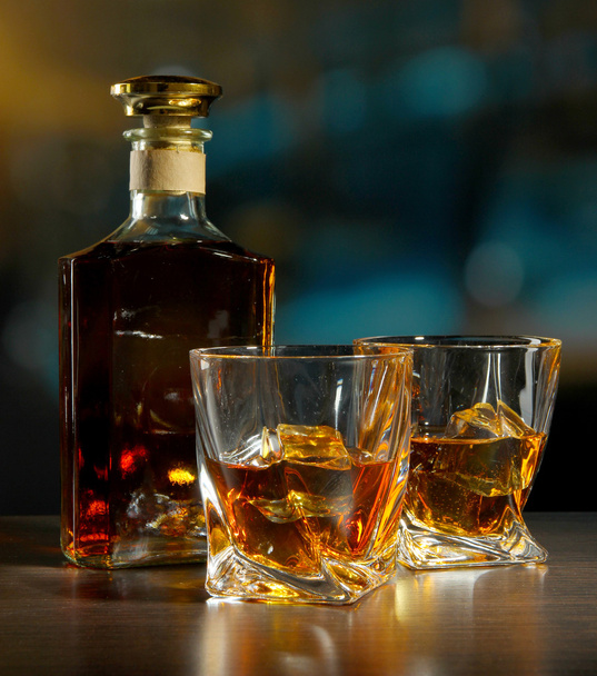 Glass of whiskey with bottle, on dark background - Фото, изображение