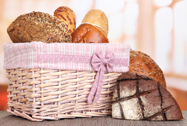 Baked bread in wicker basket on window background - Фото, изображение