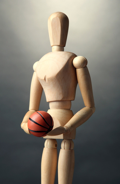 Wooden mannequin with basketball ball on grey background - Photo, Image