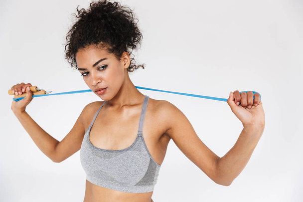 Young amazing sports fitness african woman posing isolated over white background holding skipping rope. - Foto, Bild