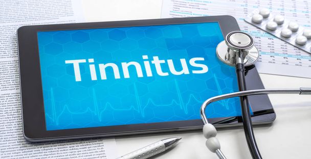 das Wort Tinnitus auf dem Display einer Tablette - Foto, Bild