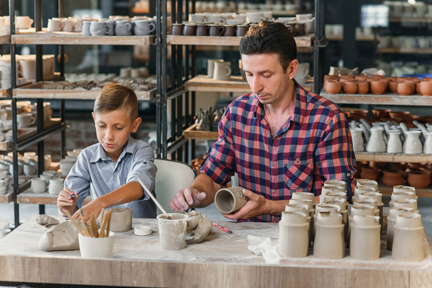 Cute middle age man with his little son having fun in the pottery. - Foto, Bild