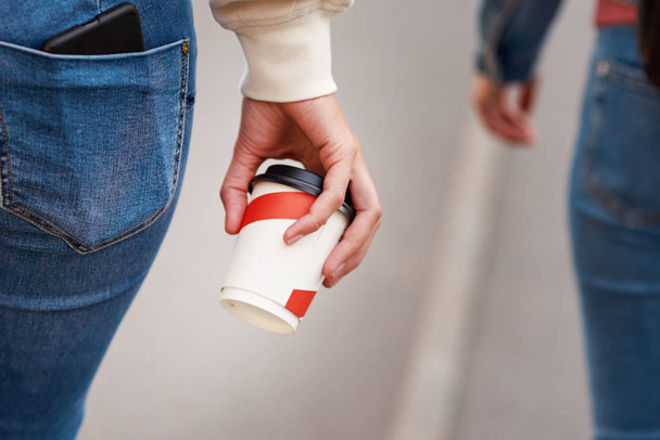 Женская рука с бумажной чашкой кофе унести на городской улице
 - Фото, изображение