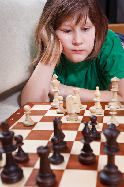 niña jugando al ajedrez tumbada en el sofá
 - Foto, Imagen