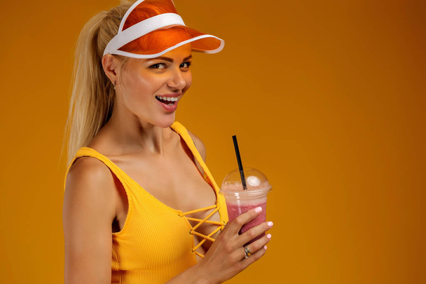blonde girl in a bathing suit and hat holding a cocktail - Photo, image