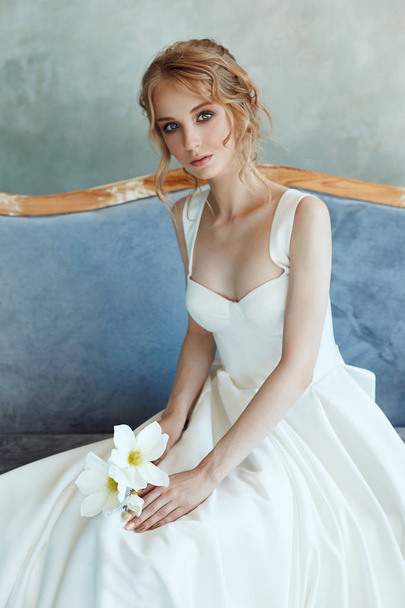 Bride in a chic long dress lying on the sofa couch. White weddin - Foto, imagen