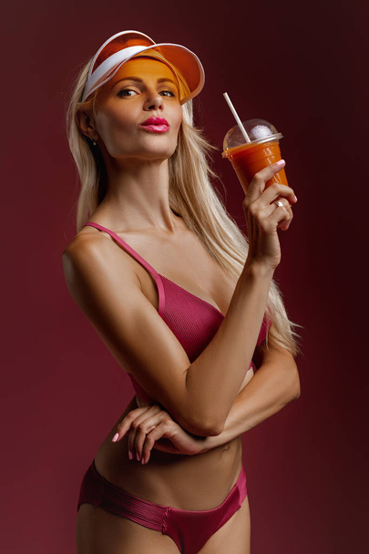 blonde girl in a bathing suit and hat holding a cocktail - Foto, Imagem