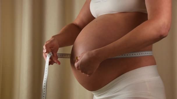 Zwangere vrouw controleert haar buik met meetlint - Video
