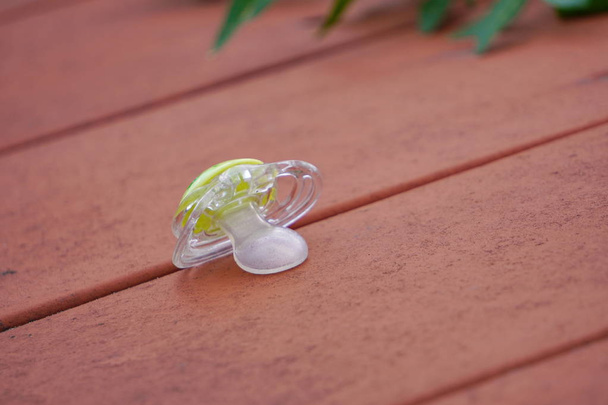 baby pacifier is on a wooden bench. nipple for babies, forgotten or lost on the Playground. - Photo, Image