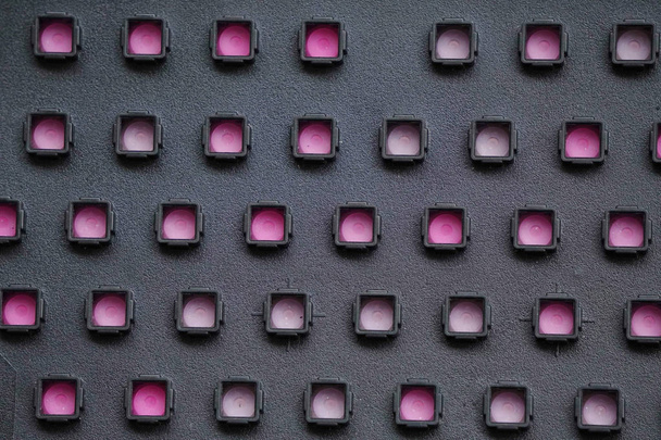 černě perforovaná plastová hmota s růžovým substrátem, symetrický objemový vzorek - Fotografie, Obrázek