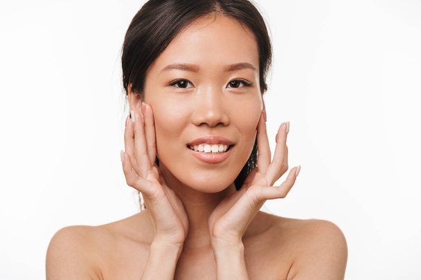Belle positive asiatique jeune jolie femme avec une peau saine posant isolé sur fond de mur blanc
. - Photo, image