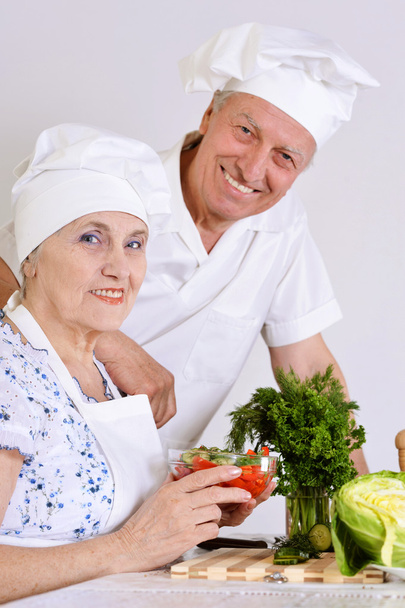 Elderly couple preparing vegetable salad together - Фото, зображення