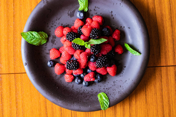 mix of fresh berries on black dish. - Foto, immagini