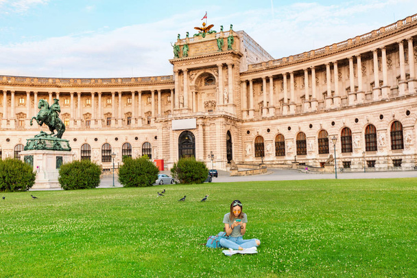 Γυναίκα που κάθεται σε ένα γκαζόν στο φόντο του παλατιού Hofburg στη Βιέννη - Φωτογραφία, εικόνα