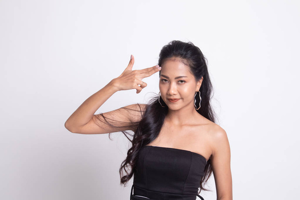 Beautiful young Asian woman holding fingers in gun gesture on white background - Фото, зображення