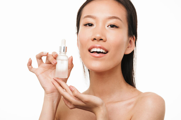 Young pretty woman with healthy skin posing isolated over white wall background holding serum oil. - Photo, image