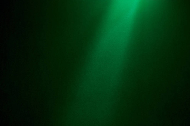 Un rayo de luz verde claro cae sobre un fondo textural verde oscuro
 - Foto, Imagen