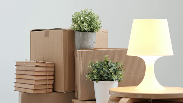 A white table lamp turns on and off against the background of cardboard boxes. - Footage, Video