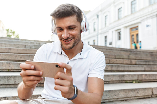 Portrait of beautiful young man smiling and holding smartphone w - Foto, Imagem