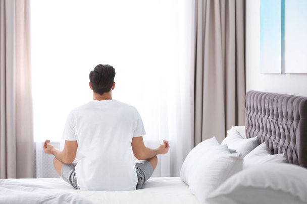 Man meditating on bed at home. Zen concept - Zdjęcie, obraz