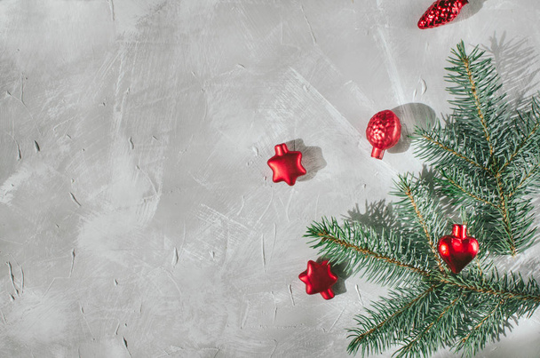 Χριστουγεννιάτικο γκρίζο φόντο με υφή. Κόκκινα Χριστουγεννιάτικα μπαλάκια και τα κλαδιά του πράσινου χριστουγεννιάτικου δέντρου είναι σε τσιμεντένιο γκρι φόντο - Φωτογραφία, εικόνα