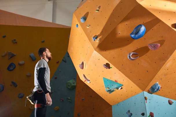 Active physically challenged boulderer stands near difficult climbing wall - 写真・画像