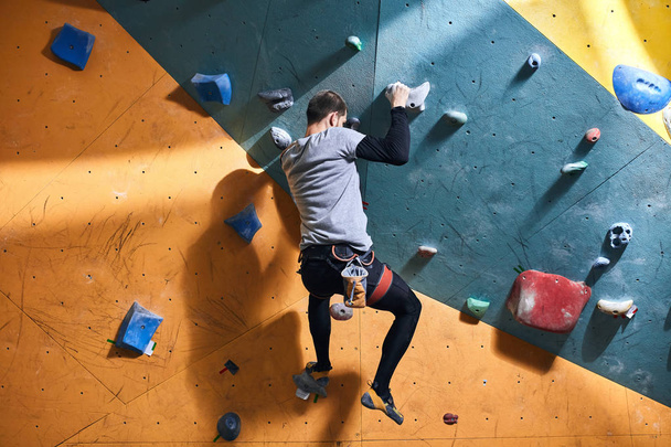 Athletic strong rock climber nearly reached the top of climbing wall - Valokuva, kuva