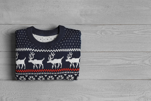 Warm folded Christmas sweater on grey wooden table, top view. Space for text - Фото, зображення