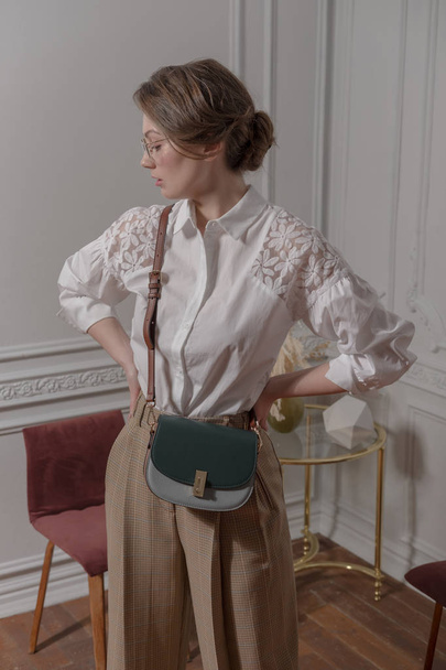 Fashionable portrait of a girl with a bag on a wide belt. - Foto, imagen