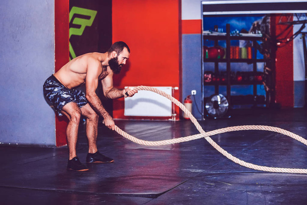 Homme barbu travaillant avec des cordes de combat à la salle de gym
 - Photo, image