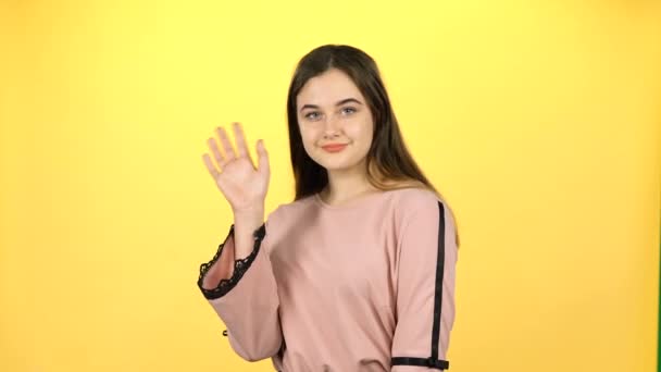 Youngful girl waving with hands on yellow background - Video